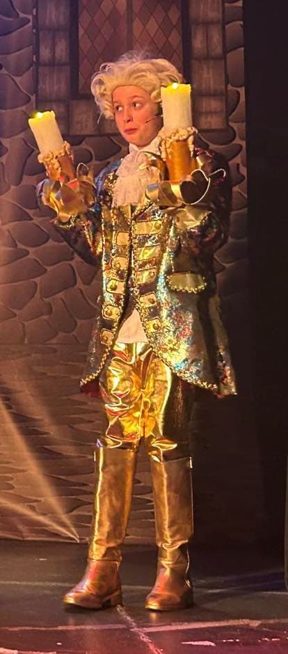 Lumière in full gold tailcoat costume holding two candles